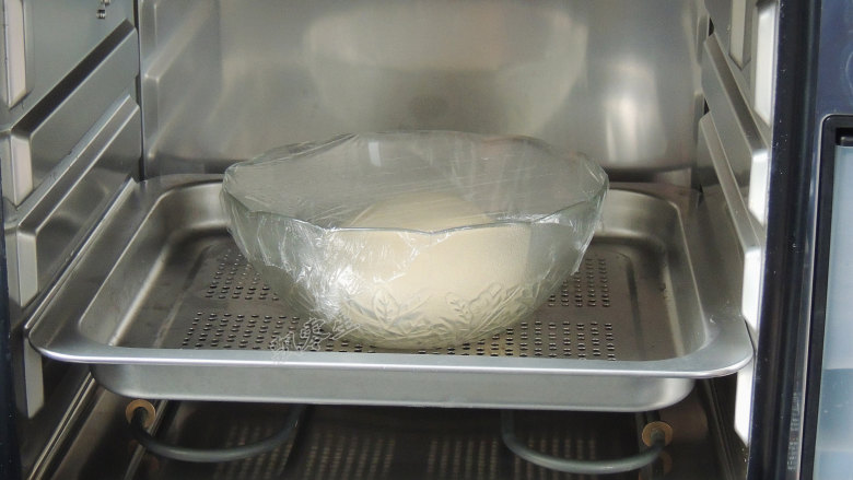 芝麻葱花面包,盖上保鲜膜或者湿布，放入蒸烤箱中，关紧烤箱门。