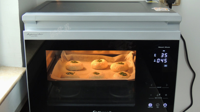 芝麻葱花面包,将烤盘放入蒸烤箱中。选择“发酵”模式，设置温度35度，时间45分钟。