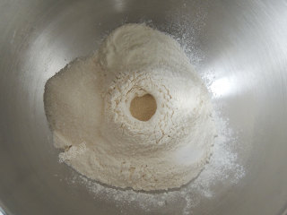 砂糖麻花面包,将所有的干性材料全部放入厨师机的搅拌桶中，酵母粉放在中间，不要和糖、盐接触。