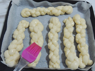 砂糖麻花面包,发酵好之后取出烤盘，同时200度预热烤箱。在面团表面刷一层薄薄的蛋液，撒上白砂糖。