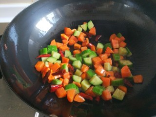 新文美食  麻辣鸡丁,倒入胡萝卜黄瓜丁翻炒均匀。