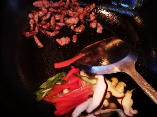 牛肉虾仁炒米线,将炒熟的牛肉到锅的一边，放入青红椒和香菇翻炒
