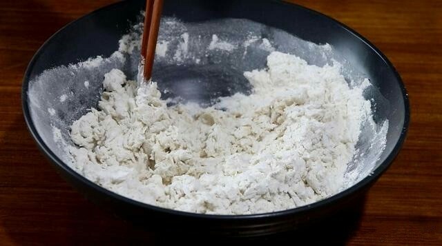 香甜红糖锅盔,将酵母水倒入面粉中，边倒边用筷子搅拌。