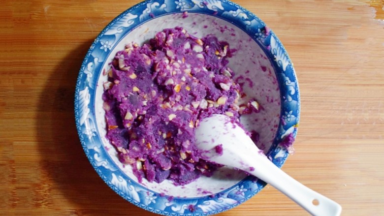 紫薯南瓜糯米糕,倒入碗中，将紫薯泥与花生碎充分混合。