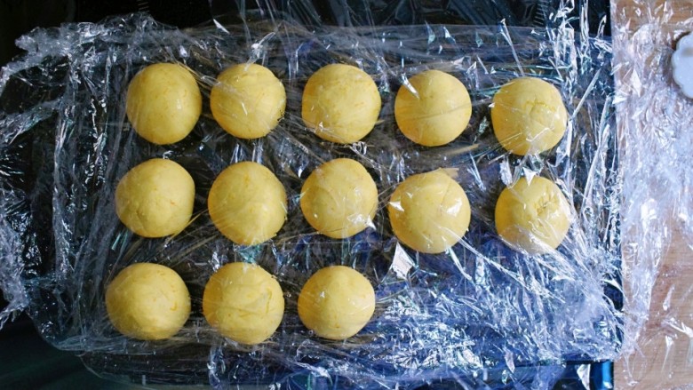 紫薯南瓜糯米糕,将饧好的面团，取约30g的面剂子，揉成球，用保鲜膜盖起来。