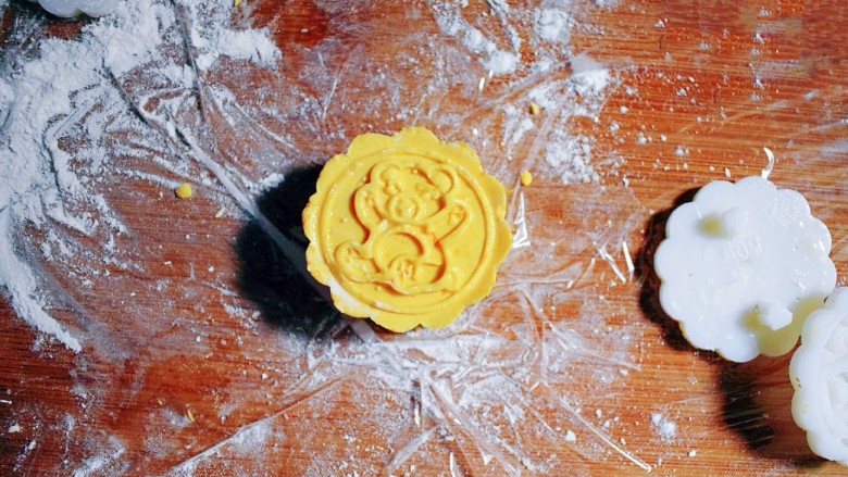 紫薯南瓜糯米糕,取月饼模具，按压出花形。（我的月饼模具是50g的，所以面团约30g，里面包的紫薯花生丸约20g，大家可以根据自己模具的大小来分剂子。）月饼模具上要抹点油哦，防黏。