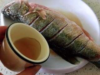 清蒸鲈鱼#年年有余#,料酒搓鱼身。