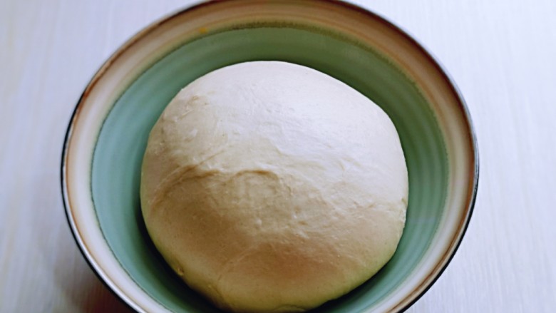 葱香四溢的全麦酸奶面包卷,取出面团，揉圆，放入器具中。放入蒸烤箱，温度35度，时间40分钟。(室温发酵也可以)