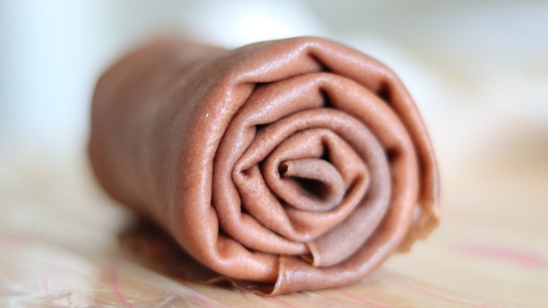 巧克力毛巾卷,两手把它卷起来，卷的时候，稍微卷紧实一些，之后包好保鲜膜冷藏定型。