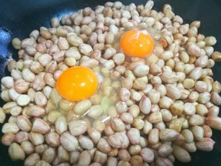 满满童年记忆的糖霜花生,花生米倒入锅中，打入两个鸡蛋搅拌均匀。