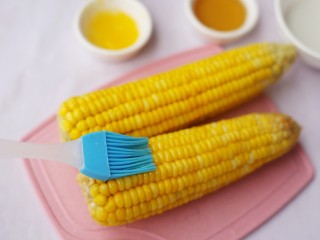 奶香味十足的烤玉米,.纸巾擦去玉米上多余的水分，将蜂蜜均匀地刷在玉米上。