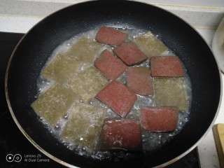 皮扎猪血炒蒜苗,不粘锅中放入适量油，将皮扎煎至两面金黄，放入猪血，加入少许清水。