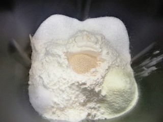 淡奶油餐包,依次加入高筋面粉和奶粉，糖和盐对角放，面粉中间挖个洞放入干酵母盖起来，启动面包机的“自动和面”程序15分钟。