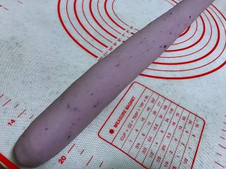 紫薯馒头，柔软超弹,在案板上搓成长条状。
