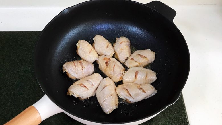 蜜汁鸡翅,腌制好的鸡翅，用厨房纸吸干表面的水份，煎制时才能上色。开中火，不粘锅里倒入少许食用油，油热后放入鸡翅。