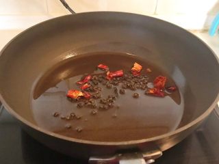 家常红烧金鲳鱼,油烧热后加入花椒粒和干红辣椒煸炒出香味