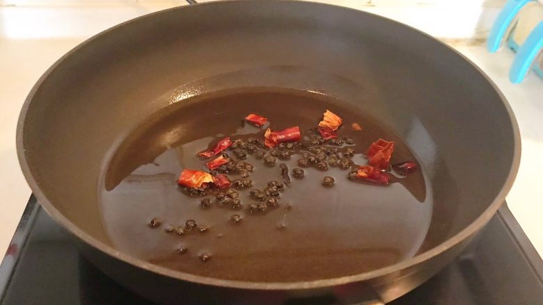家常红烧金鲳鱼,油烧热后加入花椒粒和干红辣椒煸炒出香味