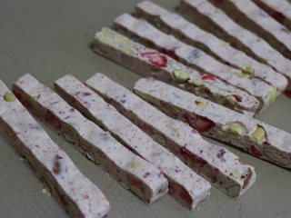 草莓牛轧糖，酸甜美味新年糖,利用方木条，比着把糖切出长条。