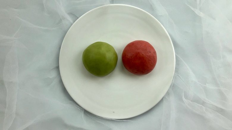 新年自制伴手礼—双色绣球酥,把（油酥）面团平均分成两份，分别揉进适量的草莓粉和麦青粉，揉至颜色均匀备用。