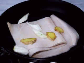 过年必备的水晶猪皮冻,锅中放入适量的葱段和姜片。