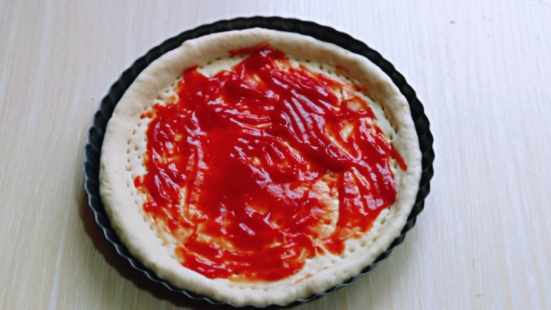 披萨新吃法～奥尔良鸡丁披萨,取一块面团擀成与披萨盘一样大的披萨皮，再用叉出洞洞，涂抹上<a style='color:red;display:inline-block;' href='/shicai/ 699'>番茄酱</a>。