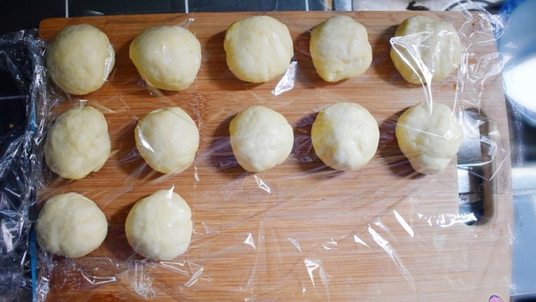 奶香葡萄干小面包（电饭锅版）,分成12个大小的面剂子，并用保鲜膜盖住，备用。