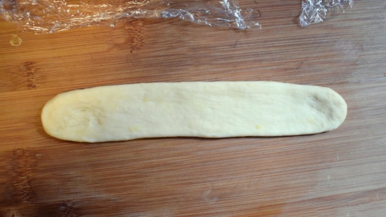 奶香葡萄干小面包（电饭锅版）,取一个面剂子，先戳成长条，再用擀面杖擀成裤带形的长条。