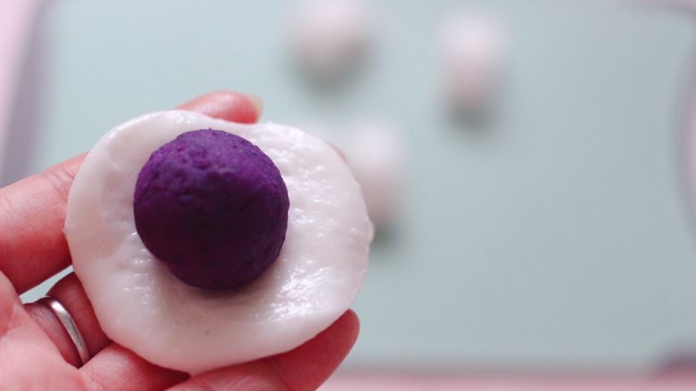 养肝抗衰老的水晶紫薯汤圆,取一份木薯粉面团，用手压扁呈薄圆形，放上一个紫薯球。
