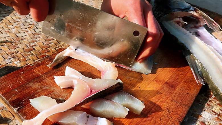 酸菜鱼#年年有鱼#,刀倾斜着片掉鱼骨，剩下净鱼肉片成片，鱼骨头剁成块儿，都用水洗干净。