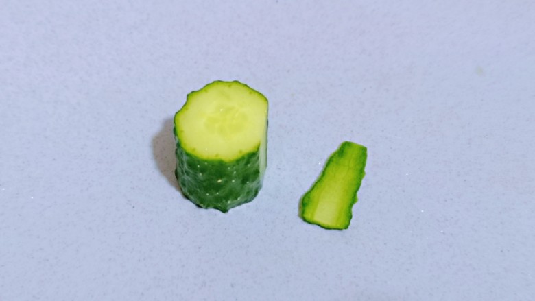 迎新春美好寓意～翠竹报春,取一段黄瓜，将黄瓜的一侧切掉一片，这样摆放在盘子中会比较稳。