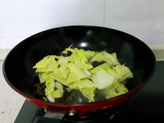大白菜炒木耳,放入白菜叶子，一面炒一面加入盐，放入葱叶，翻炒均匀。
