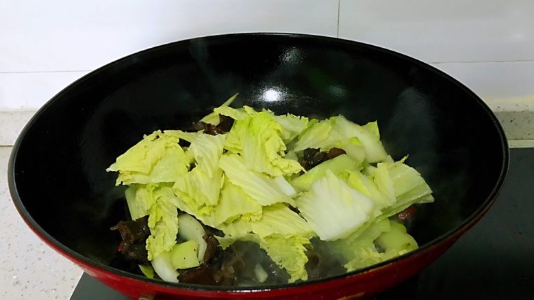 大白菜炒木耳,放入白菜叶子，一面炒一面加入盐，放入葱叶，翻炒均匀。