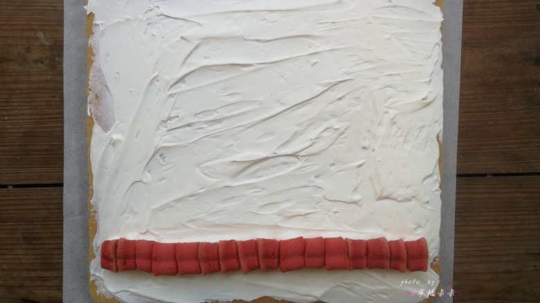 彩绘玫瑰蛋糕卷,将晾凉的蛋糕片放在干净的油纸上，没有彩绘玫瑰的那面朝上，四周切平整，底端45度斜切，然后抹上打发的淡奶油，铺上一排夹心用的心型红丝绒蛋糕，铺夹心的时候要挨着铺紧凑些，不能留有空隙