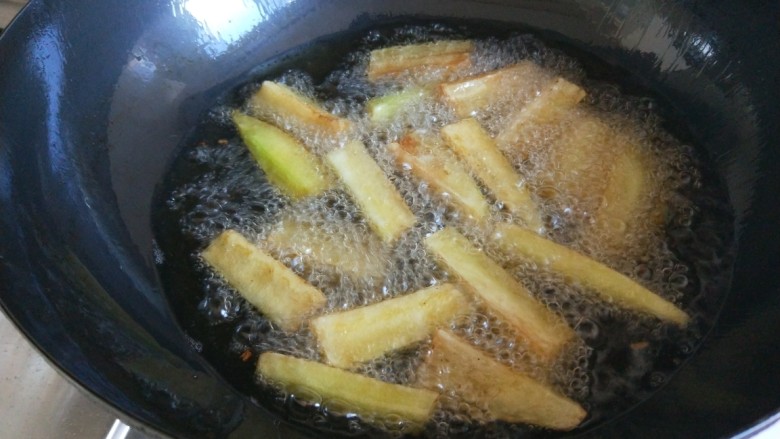 鱼香茄子  新文美食,锅中倒油烧七成热倒入茄子条。