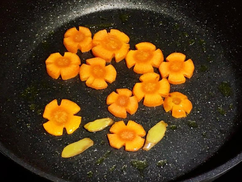 鲜蔬粉丝煲,锅内倒入2茶匙的油，放入姜片、红萝卜片炒香。