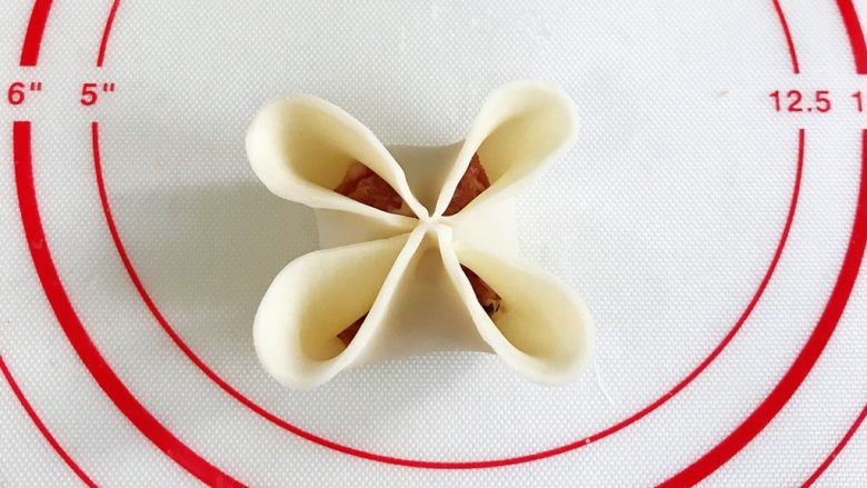 四喜蒸饺,先给饺子皮对角刷点水，筷子对角夹紧，再把每一个花瓣边缘捏薄些。
