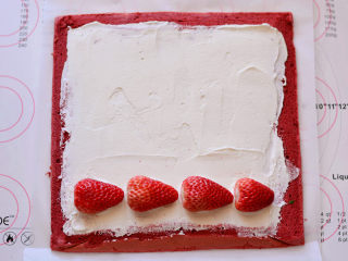 红丝绒蛋糕卷,把晾凉的蛋糕卷放在一张油纸上，抹上打发好的淡奶油，摆放上草莓，再抹一屋奶油，把草莓包裹起来