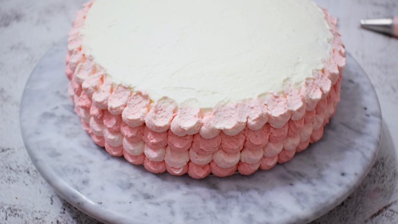 皇冠彩虹蛋糕,淡粉色的也按照这样方法挤在粉色上，这样相互交替直到蛋糕周围都挤满