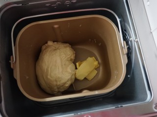 面包机版炼奶面包,第一次揉面结束后加入切成小块的黄油