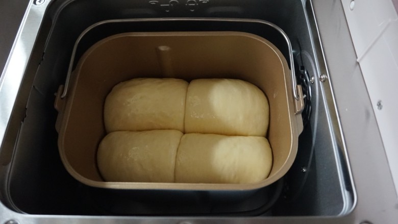 面包机版炼奶面包,发酵好的面包胚有七八分满了，在表面刷上全蛋液