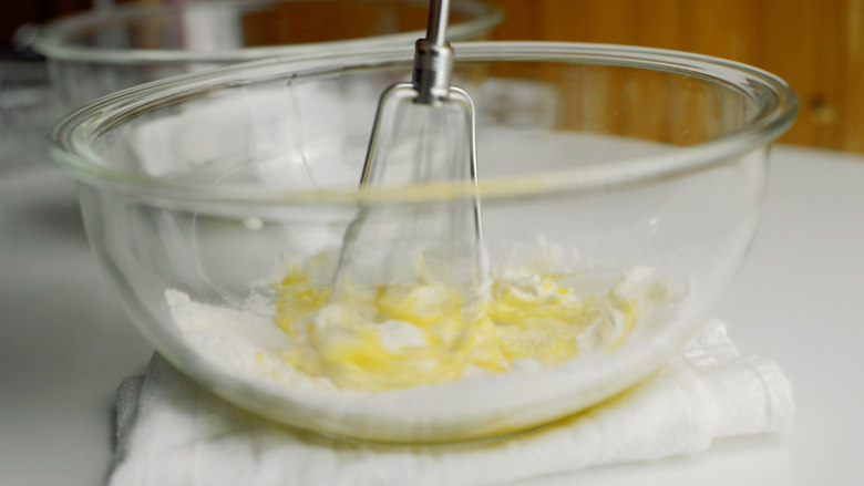 老酸奶舒芙蕾松饼,用打发过蛋清的打蛋器搅拌蛋黄盆。