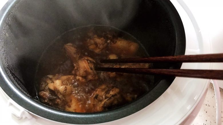 可乐鸡根翅（电饭煲版）,约摸15分钟左右的样子，打开锅盖，用筷子把鸡根翅翻个面，然后盖上锅盖继续煮