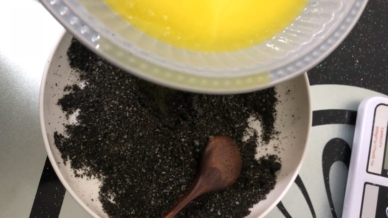 芝麻流心汤圆,黄油隔水融化成液态后少量多次加入蛋白糖芝麻粉中，搅拌均匀。