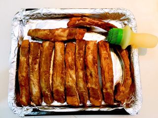 #猪肋排#  秘制香辣烤肋排,取一个烤盘，在烤盘里铺上锡纸，把猪肋排放入烤盘，均匀的刷一层玉米油