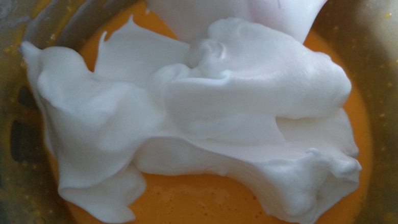 咸蛋黄肉松盒子蛋糕,分三分之一的蛋白霜到蛋黄糊内，用刮刀翻拌均匀。