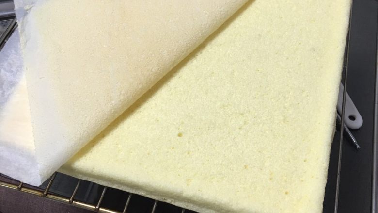 椰蓉豆沙蛋糕卷,掀掉烤盘纸冷却一下。