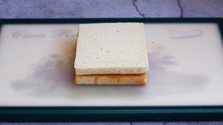 芒果酸奶三明治,将另外一片吐司切片放在上边，轻轻压一下，使两片吐司切片粘在一起。