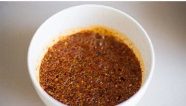麻辣口水鸡,用无水的锅铲把花椒拦住，将油倒入辣椒面的碗里。一个简单的辣椒油就做好啦。