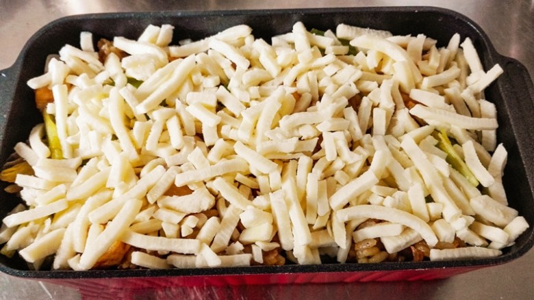 什锦咖喱焗饭,把炒好的米饭铺在容器中。在米饭上面。铺上一层奶酪丝。一定要铺均匀。
