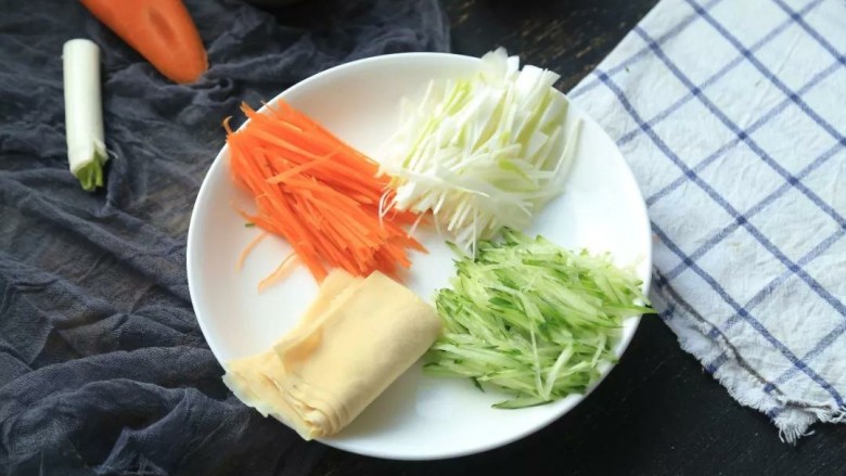 京酱肉丝,2.大葱、胡萝卜、黄瓜洗净切成细丝备用，薄百叶在热水中浸泡10分钟，然后切成巴掌大小的方形，并将它们整齐的码放在盘子上；